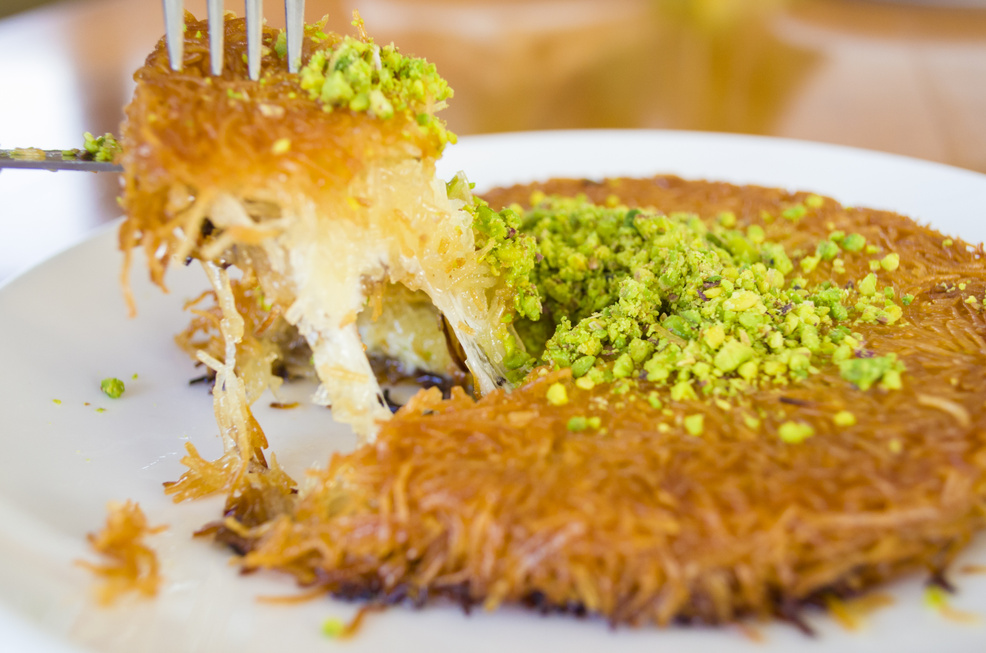 turkish dessert kunefe, kunafa, kadayif with pistachio powder and cheese hot eaten a sweet